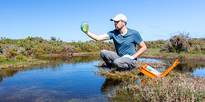 Scientist collects river water for testing.