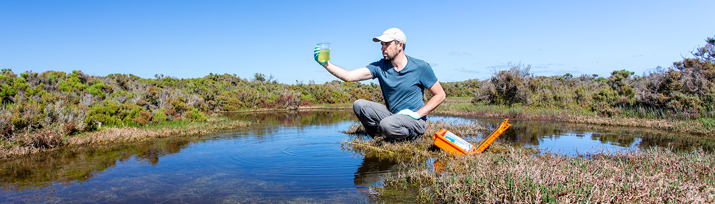 Scientist collects river water for testing.
